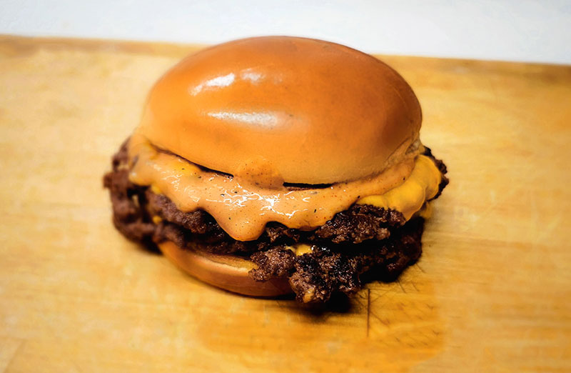 Wilson’s Grill Hilliard catering smash burger with melted cheese oozing down its sides and house-made Plunder sauce on a toasted brioche bun